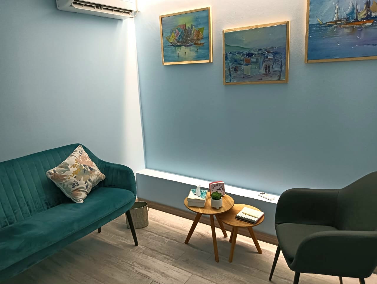 Foto de un box con un sillón de color azul y tres cuadros colgados en la pared